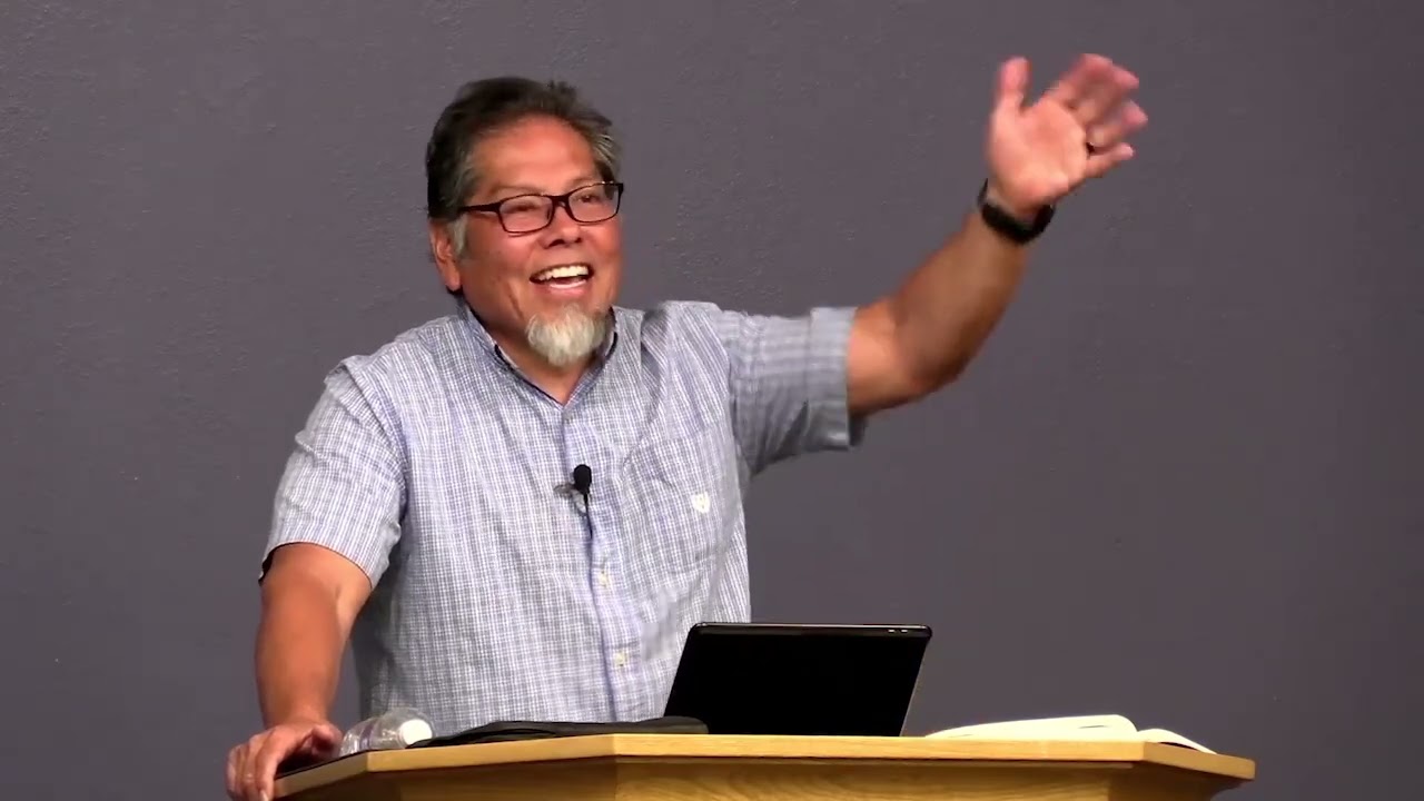 Pastor Tom Ruiz teaching Deuteronomy 13:1-5 with a raised hand and big smile